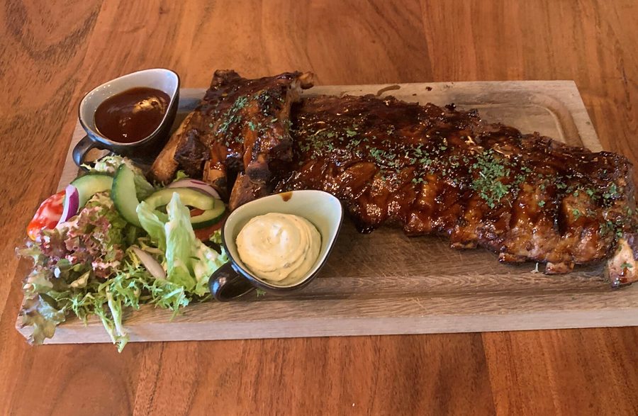 Spareribs op een houten plank met salade en saus